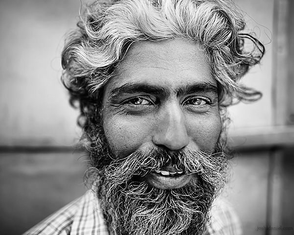 A 28mm wide angle black and white portrait of a smiling man with beard