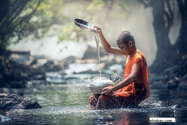 Buddhist Monk, sitting by a river.  Pouring a water from a height and sitting in contemplation.